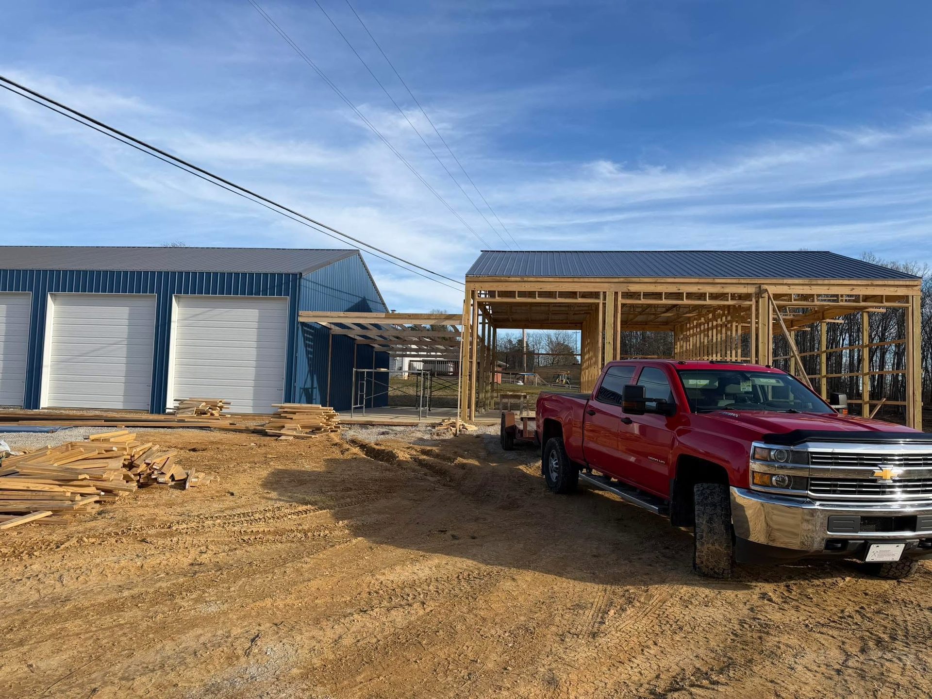 Pole barn structure under construction next to a completed metal building